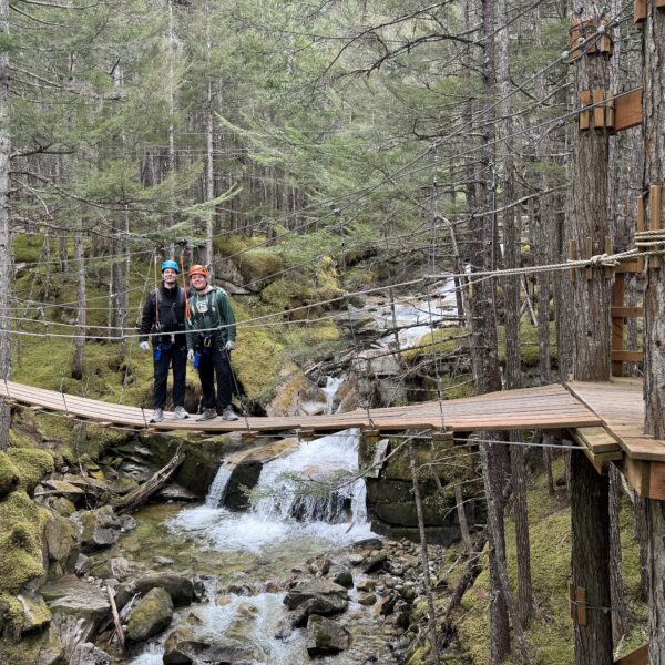 Two men zip lining near a waterfall